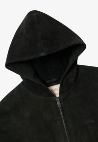 Black suede zip-up hoodie with visible fleece lining inside hood and subtle brand label near chest.