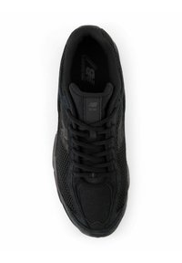 Sneaker sportivo nero con tomaia in rete, colletto imbottito e suola testurizzata. Include lacci neri e il logo New Balance sul lato.