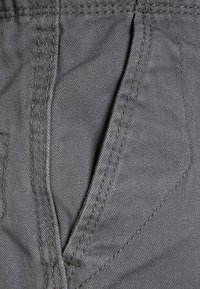 Grå denimtyg med ett diagonalt twillmönster. Har en framfick med synliga sömmar och en texturerad yta.