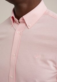 Světle růžová košile na knoflíky z bavlněné směsi, s klasickým límečkem, dvěma knoflíky a jemně vyšitým logem na prsou.