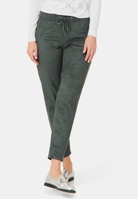 Groene nepleer broek met een tapered leg, elastische tailleband en trekkoord. Voorzien van zijzakken en zijkant lijnen.