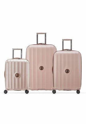 Set of three lightweight, pink hard-shell suitcases with vertical ribbed texture, retractable handles, and four wheels for easy mobility.