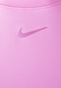 Tejido atlético rosa con una textura suave; presenta un logotipo de Nike tonal en un rosa ligeramente más oscuro, cerca del centro superior.