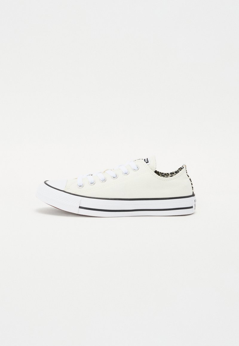 Baskets en toile blanches avec des accents noirs, présentant un bout arrondi classique, des lacets plats et un détail en imprimé animal au niveau du talon.