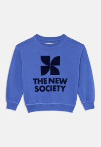 Zils džemperis, kas izgatavots no mīksta auduma, ar noapaļotu izgriezumu. Ievērojama melna grafiskā dizaina elementi ar tekstu "JAUNĀ SOCIĀLĀ" zem tā.