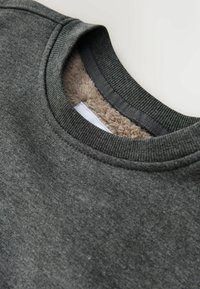 Sweatshirt gris foncé avec un extérieur texturé, un col en polaire, une encolure côtelée et une surface subtile et lisse.