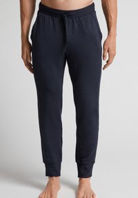 Marineblauwe sweatpants van zachte stof met een elastische tailleband, een trekkoorddetail en ribgebreide boorden. Beschikt over een frontzak.