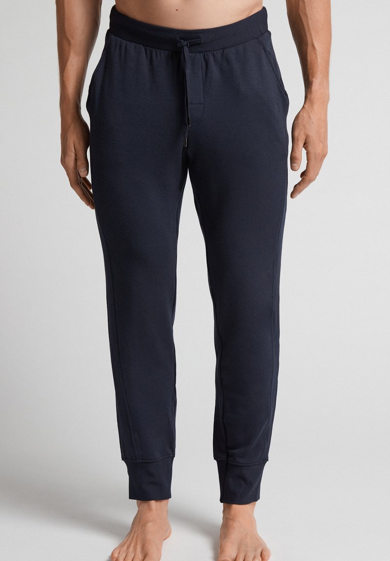 Marineblauwe sweatpants van zachte stof met een elastische tailleband, een trekkoorddetail en ribgebreide boorden. Beschikt over een frontzak.