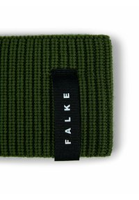 Tessuto a maglia a coste verde scuro con un'etichetta nera che mostra il nome del marchio "FALKE" in lettere bianche.