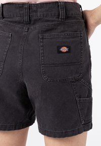 Černé bavlněné šortky s texturovaným povrchem, zadními kapsami a malou vícolorovou nášivkou "Dickies" na pravé kapse.