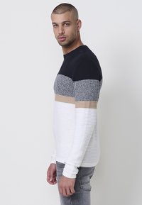 Sudadera de punto con rayas en azul marino, gris, beige y blanco. Textura acanalada, cuello redondo y mangas largas; corte casual.