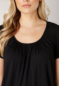 Zwart topje met een ronde hals, plooidetails aan de voorkant en korte mouwen, gemaakt van zachte, lichte stof.