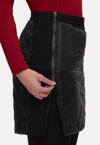 Quilted black skirt with a side zipper and stretchy waistband, made from contrasting materials, showcasing a chevron pattern.