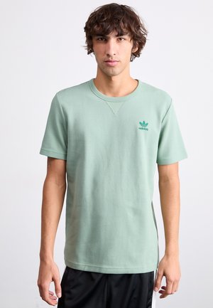 Zöld, rövid ujjú póló, textúrált anyagból, kerek nyakkivágással és egy kis zöld Adidas logóval a mellkason. Lazán illeszkedő fazon.