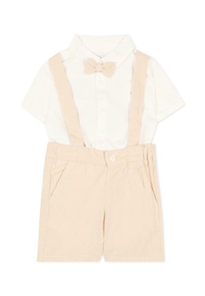 Camicia bianca a maniche corte con colletto e papillon beige, abbinata a pantaloncini beige con bretelle e tasche laterali.
