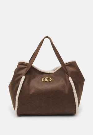 Sac fourre-tout en daim marron avec garniture en shearling blanc et fermoir ovale doré, avec deux bretelles sur fond blanc uni.