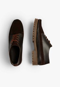 Zapatos de cuero y ante marrón con cordones marrones, suela de goma plana y detalles de costura. Presentan una puntera redondeada y texturas contrastantes.