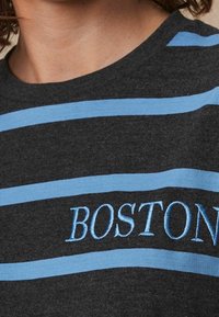 Szara bawełniana koszulka z poziomymi jasnoniebieskimi paskami oraz haftowanym napisem "BOSTON" w jasnoniebieskim kolorze, umieszczonym w centralnej części.