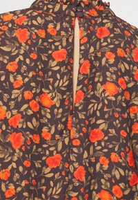 Mörkblommig klänning med brun bas, som har livfulla orange blommor och gröna blad. Nyckelhål i ryggen med rynkad halsringning och knappar.