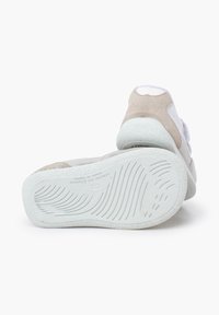 Witte en beige sneakers met een textuur, flexibele zool. Het bovenwerk heeft een mix van materialen en een minimalist design.