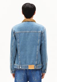 Lichtblauw denim jasje met een bruine corduroy kraag, voorzien van knoopsluiting, een logo-patch op de achterkant en een klassiek gestructureerd ontwerp.