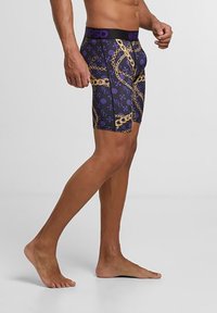 Fialové boxerky s vzorovaným dizajnom a motívom zlatého reťazca, vyrobené z elastického materiálu, s elastickým čiernym pásom.