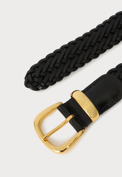 Ceinture en cuir tressé noir avec boucle métallique dorée brillante et passant sur un fond clair.