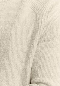 Gestructureerde crème-kleurige stof met verticale ribbels, met een zachte, donzige oppervlakte en een ontspannen pasvorm. Geen opmerkelijke accenten of hardware.