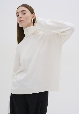 Přerostlá, dlouhá turtleneck svetr v měkké bílé látce, s uvolněným střihem, vroubkovanými manžetami a rovním lemem.