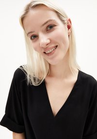 Schwarzes, kurzärmliges Oberteil mit tiefem V-Ausschnitt. Der Stoff wirkt weich mit einer glatten Textur und minimalen Designdetails.