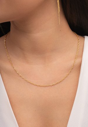 Collar de oro con formas ovaladas y redondas entrelazadas. Textura de cadena visible; se lleva cerca del cuello sobre piel desnuda.