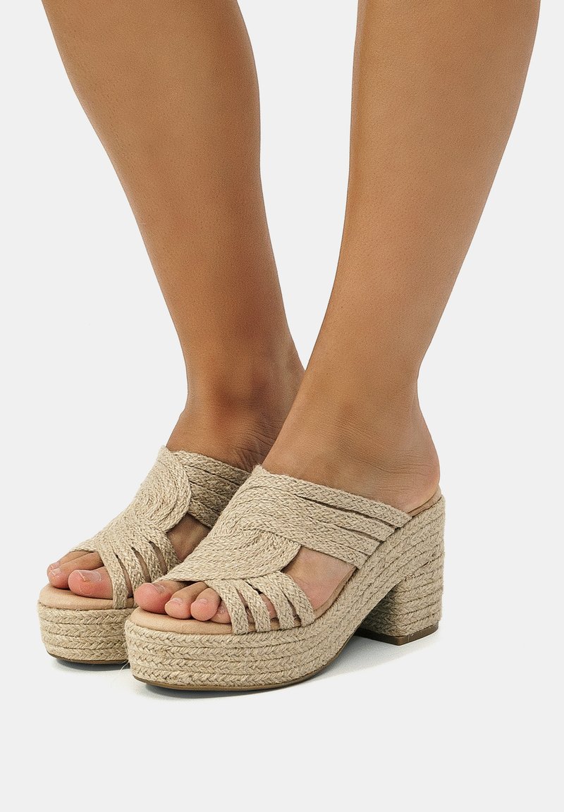 Sandales à plateforme tissées beiges avec un talon bloc haut, dotées de brides croisées et d'un design à bout ouvert. Détail en corde texturée sur la semelle.