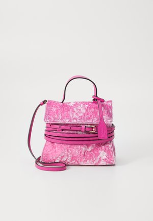 Pink velvet handbag with textured surface, removable shoulder strap, top handle, and layered design accents. Features a labeled tag.