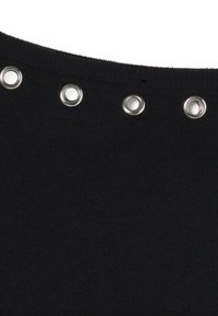 Primer plano de tela negra con cuatro ojales de metal plateado, espaciados uniformemente cerca del borde superior.