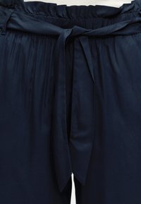 Σκούρο μπλε παντελόνι με ελαστική μέση και δέσιμο από ύφασμα στη μέση μπροστά.