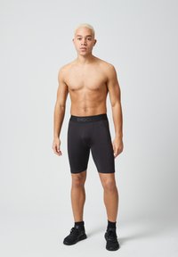 Pantaloni sportivi neri con una vestibilità aderente. Realizzati in tessuto elasticizzato, presentano una vita spessa con il marchio "SNOCKS" in testo nero.
