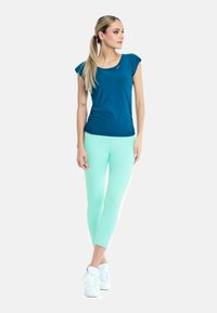 Žalias trumpas rankovėmis marškinėliai su apvaliu kaklu, derinami su mėtų žaliai leggings. Leggings turi lygų paviršių, su baltais akcentais šonuose.