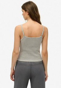 Grijze geribde tanktop met dunne bandjes, voorzien van een aansluitend design. De achterkant heeft een ronde halslijn en subtiele decoratieve elementen.