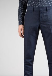 Námořnické modré kalhoty na míru s rovný frontem, slim fit a hladkou texturou. Obsahují boční kapsy a dva poutka na pásek.
