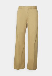 Beige, vida byxor i lättviktig bomull. Har framfickor och en slät yta, med rena sömmar och dragkedjestängning.