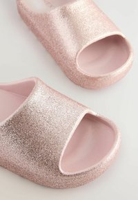 Glanzende roze slide sandalen met een open teen, met een gladde, glanzende textuur en een afgeronde vorm. Geen zichtbare hardware of patronen.