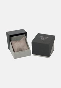 Kaks Guess brändi kella kasti, üks avatud halli padjaga sees ja teine suletud logoga peal. Mõlemad musta ja halli tooni.