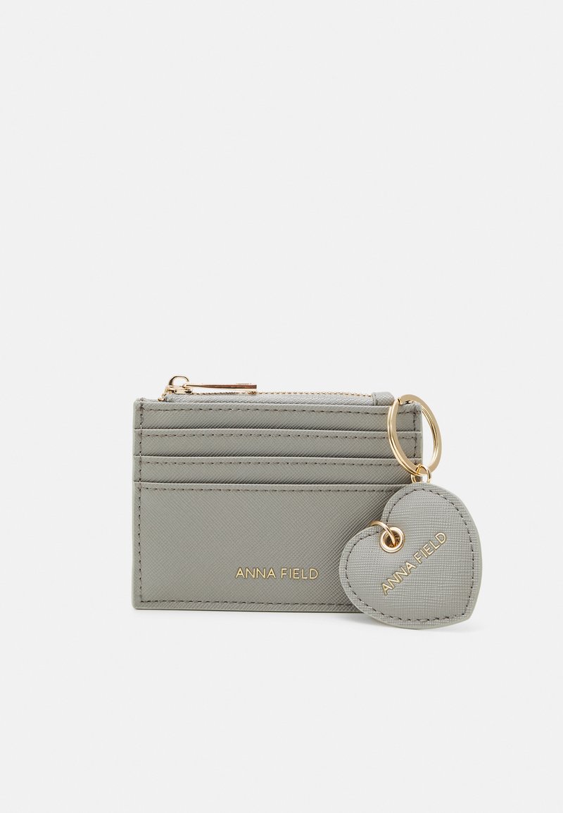 Gray leather cardholder with multiple card slots, gold hardware, and a heart-shaped keychain. Features embossed brand name.
