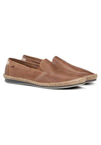 Zapatos marrones de slip-on perforados con una suela beige cosida, que presentan un sutil logo en el costado y una textura suave.