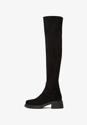 Schwarze Overknee-Stiefel aus weichem Wildleder mit einem klobigen Absatz, die ein glattes Design und elastische seitliche Einsätze für eine einfache Passform aufweisen.