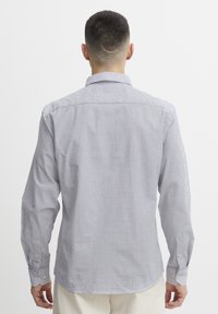 Chemise à manches longues rayée bleu et blanc, avec un col à rabat, coupe ajustée et poignets à boutons ; fabriquée dans un tissu doux et texturé.