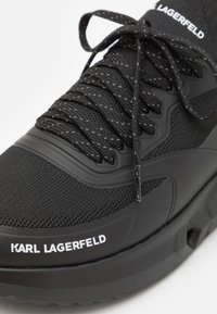 Mustad sneaks tekstuurse võrkkattega, kummist aktsentide ja paksu tallaga. Külje peal on logo "KARL LAGERFELD" ja kontrastsed paelad.
