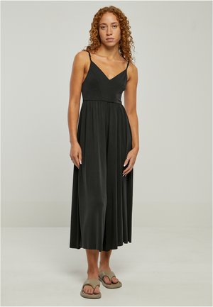 Schwarzes Midi-Kleid mit tailliertem Oberteil, V-Ausschnitt und dünnen Spaghettiträgern; aus glattem Stoff mit einem fließenden Rock gefertigt. Model trägt Sandalen.