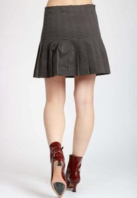 Gonna grigia plissettata con una cintura strutturata e cuciture verticali sottili, abbinata a stivaletti rossi lucidi con punta appuntita e tacco.