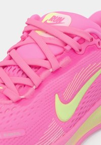 Nike teka za tek featuring svetlo roza mrežasti zgornji del, zeleni detajli in teksturiran podplat. Vključuje roza vezalke in logo "RUN" na jeziku.